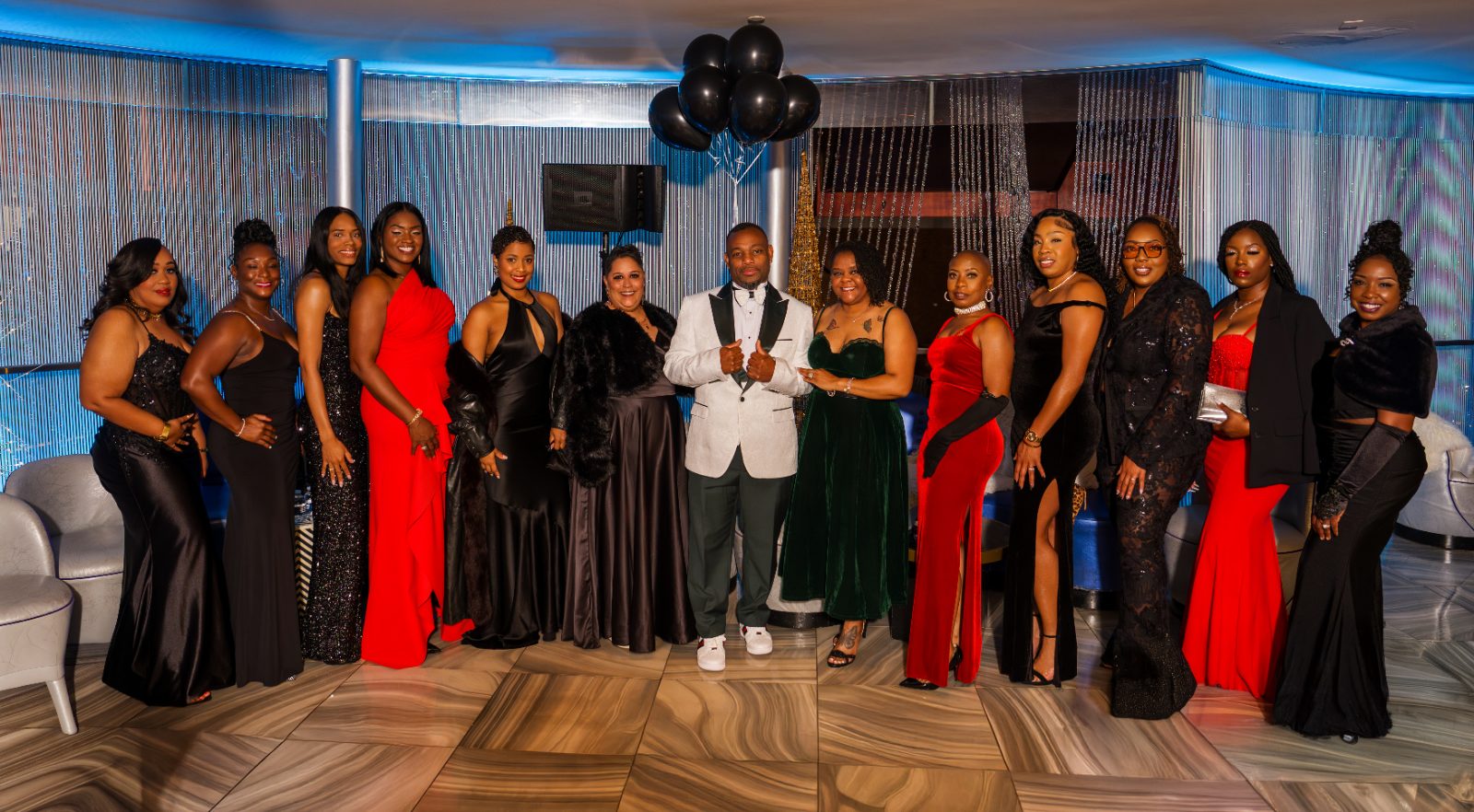 Las Vegas concert photoshoot — the full group in gowns and black tie under the suite lights