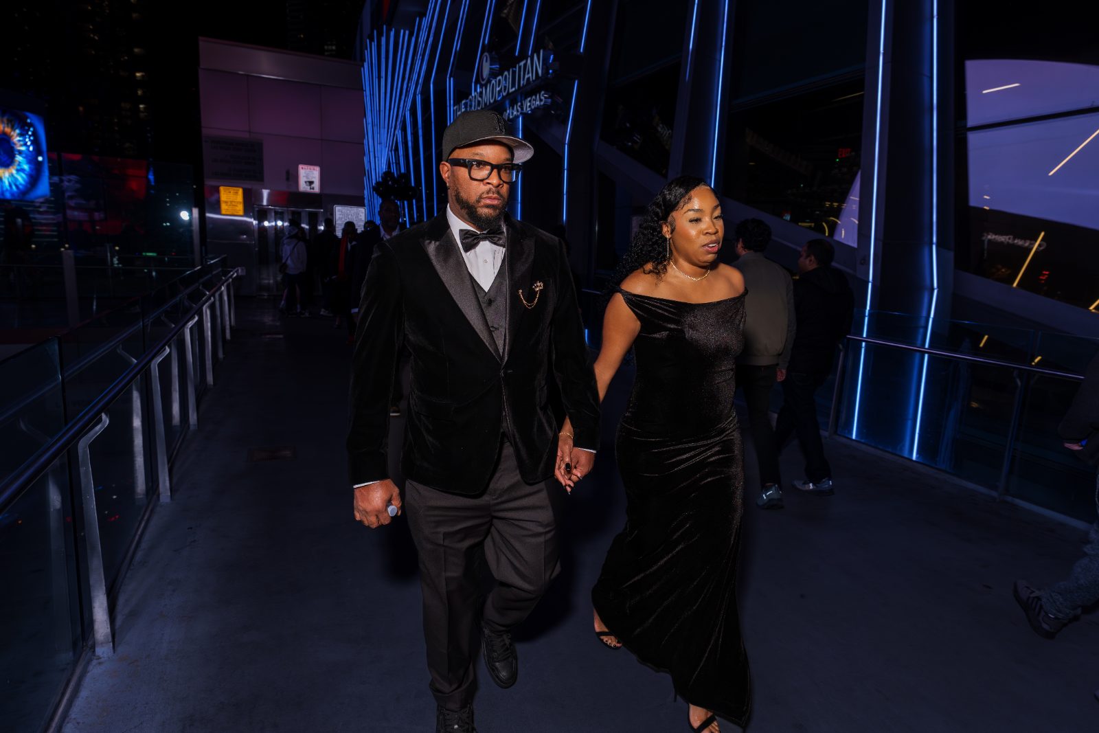 Las Vegas concert photoshoot — couple in black velvet walking hand in hand past the Cosmopolitan